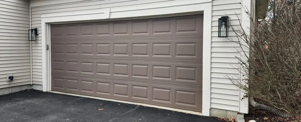 Before: taupe raised panel garage door on a cream sided home