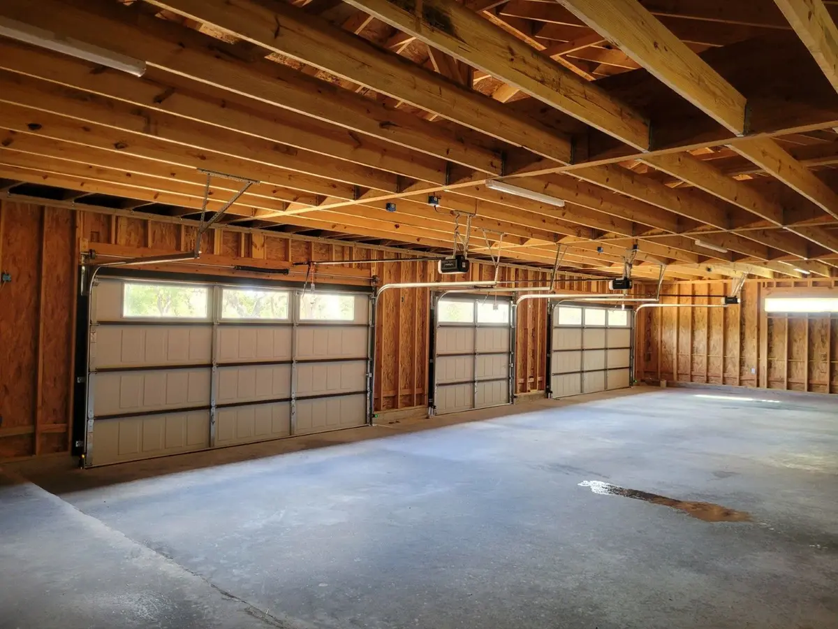 Three sectional overhead doors with windows inside a large timber framed garage bay