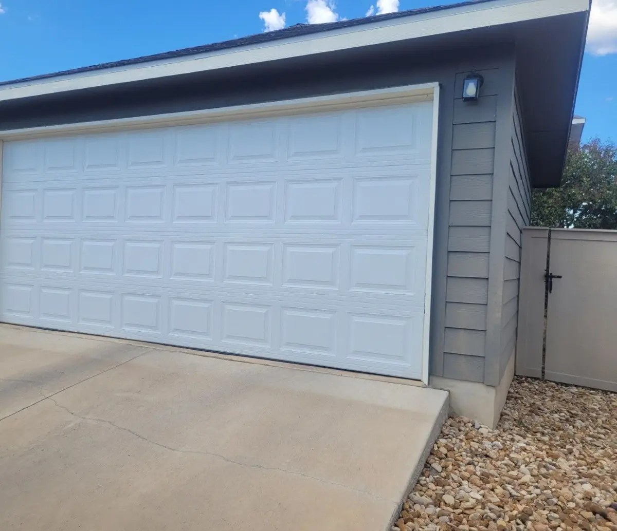 White raised panel double garage door on a grey sided garage
