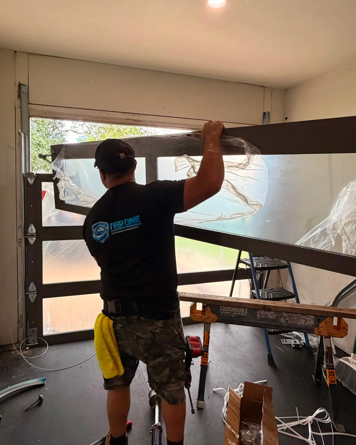 Tier One technician installing a full view glass garage door