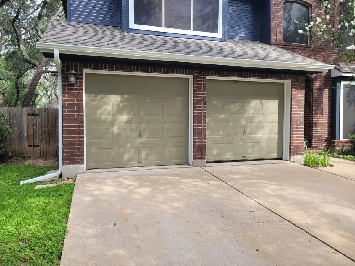 Before: two sage green single garage doors on a brick Southwest Austin home