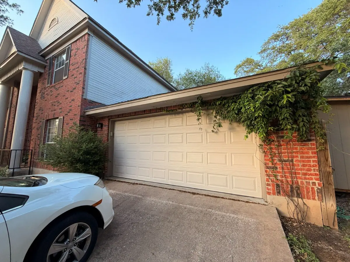 Before: almond raised panel double garage door on a brick Northwest Austin home