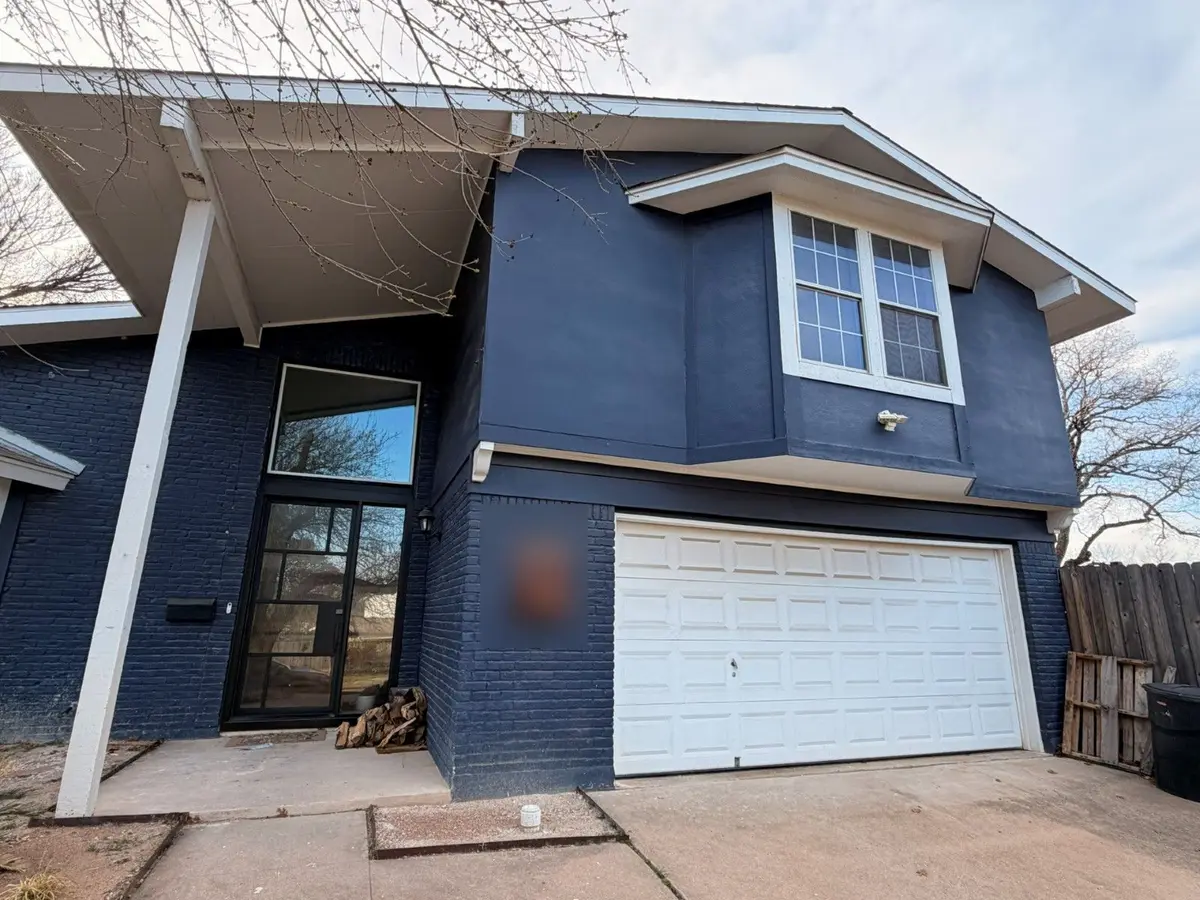 Before: white raised panel double garage door on a dark blue two story home