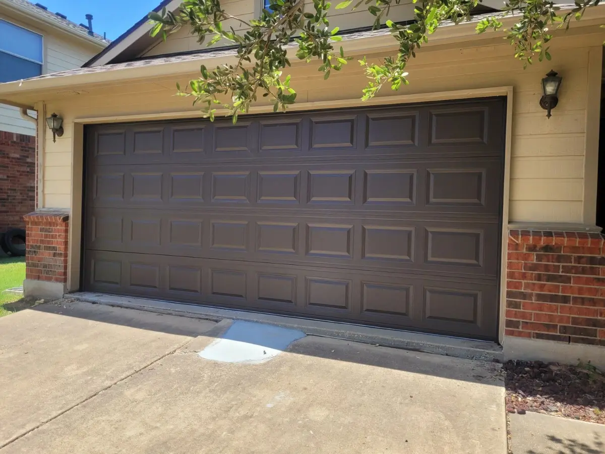 Dark brown raised panel double garage door on a home with brick columns, installed by Tier One