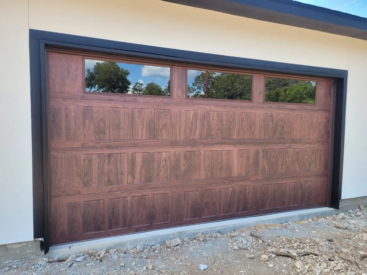 Close-up of a wood tone garage door with three windows and black trim
