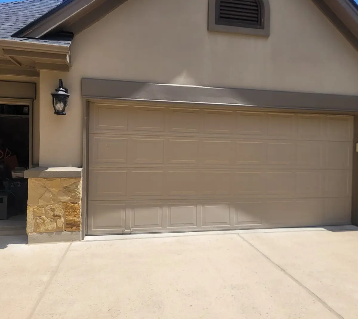Before: tan double garage door on a stucco and stone home