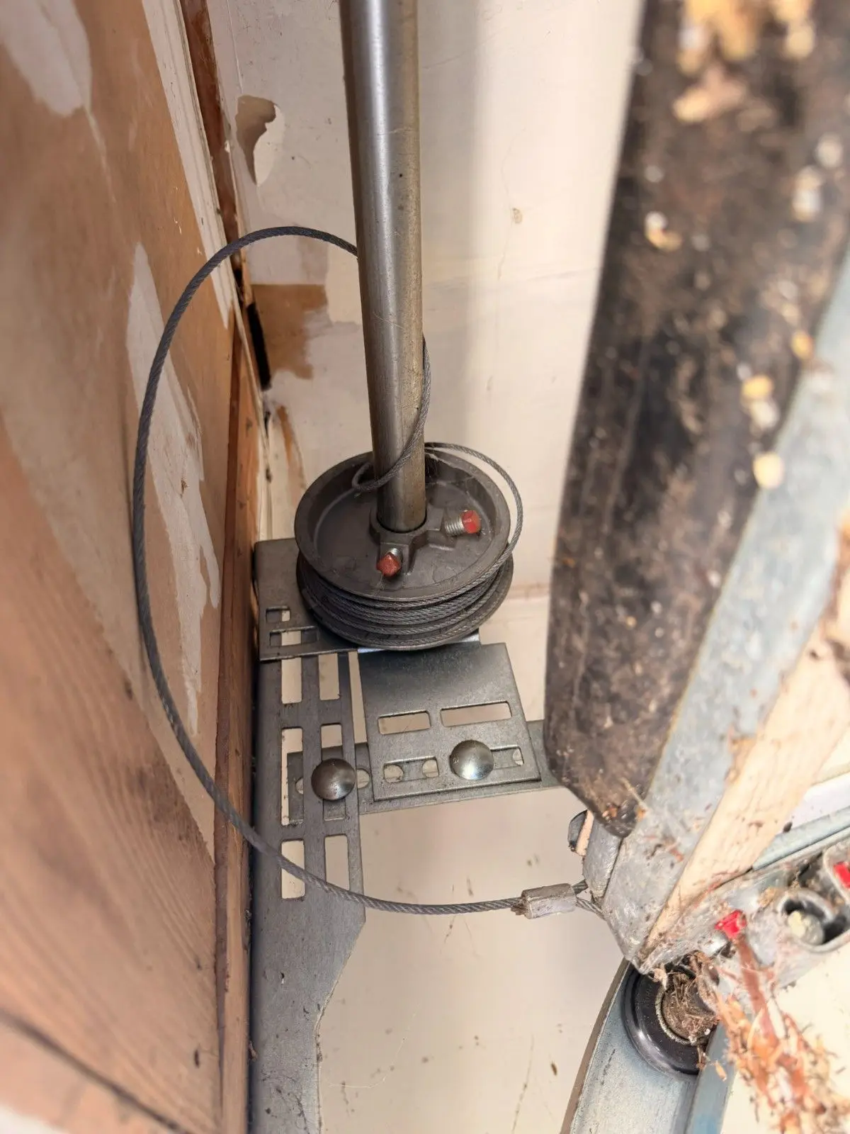 Garage door cable that has come off its drum and hangs in a loose loop beside the track