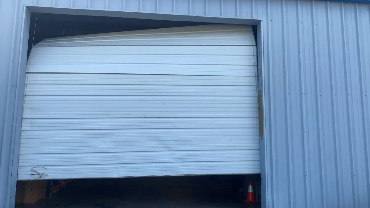 Sectional door on a metal building buckled and pushed out of square