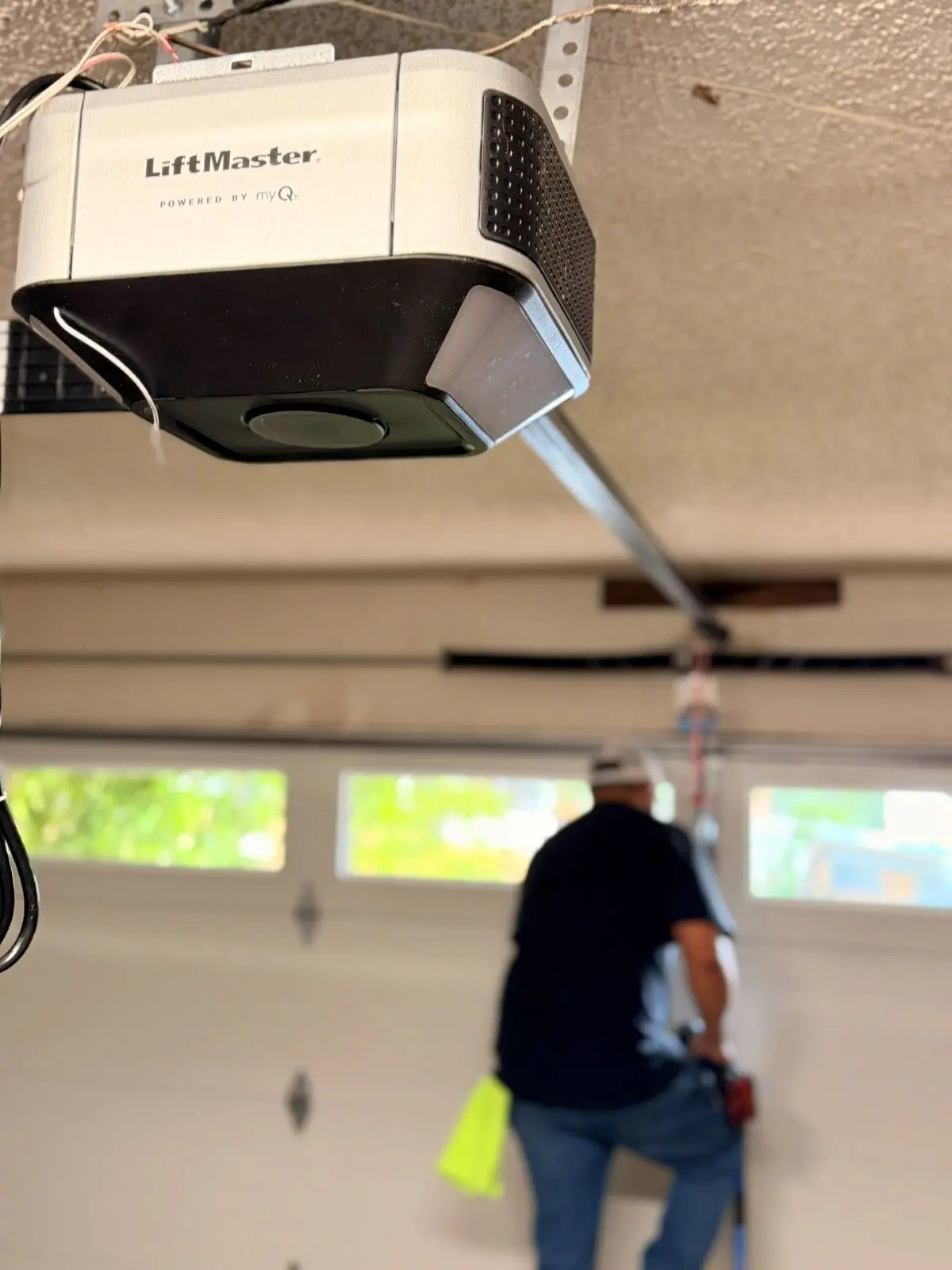 Technician working at a garage door below a LiftMaster opener