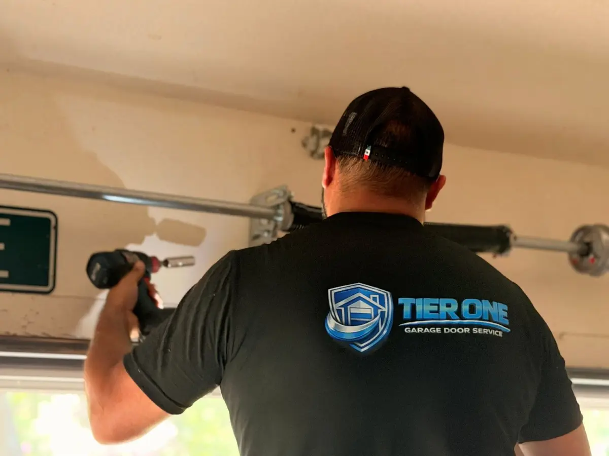 Tier One technician working at the spring shaft above a garage door